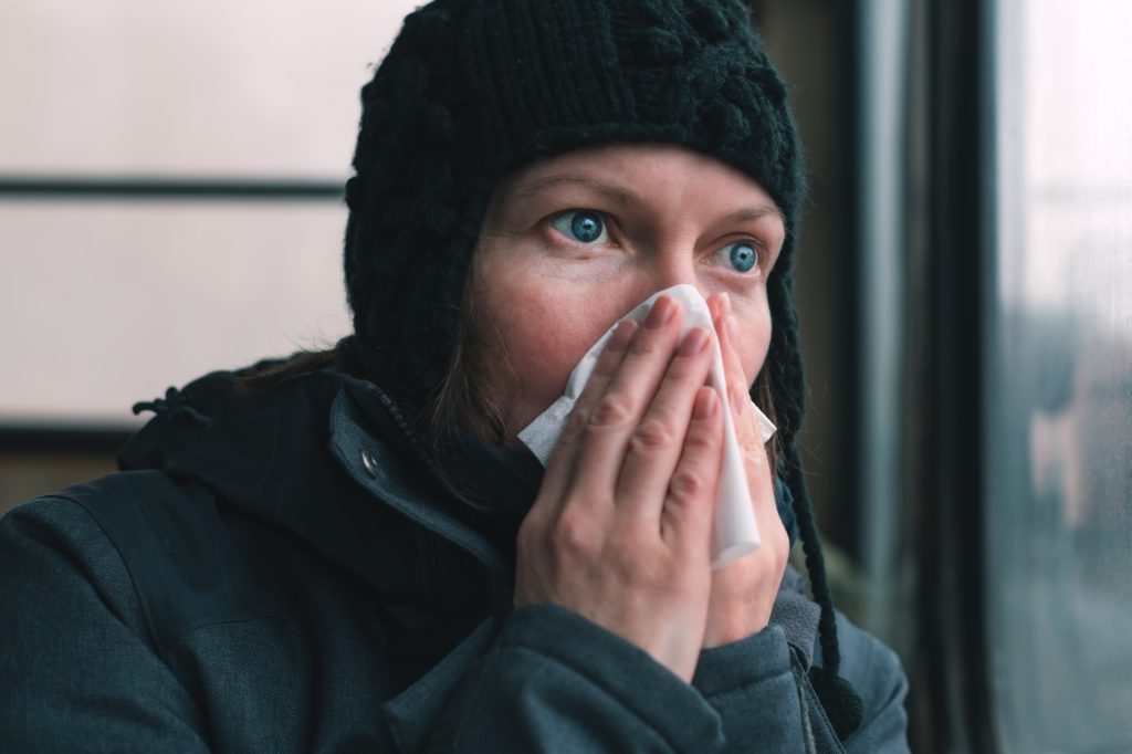 Woman blowing her nose into paper handkerchief